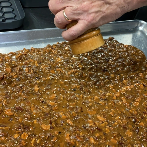 Cracked pepper being hand-ground over a batch of butter crunch